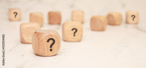 wooden blocks with question marks on a marble surface, symbolizing uncertainty and curiosity photo