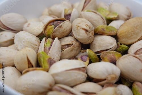 Roasted pistachios showing green and purple hues filling a bowl photo