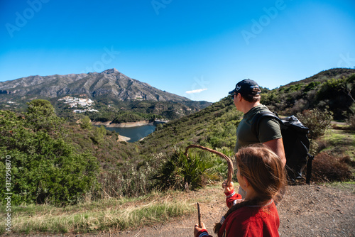 Caucasian male adult and female child hiking in scenic mountain landscape, La Concepcion reservoir in Marbella
