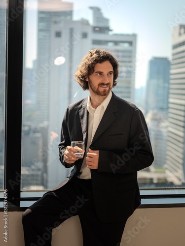 Thoughtful Businessman Gazing Through Office Window at Cityscape