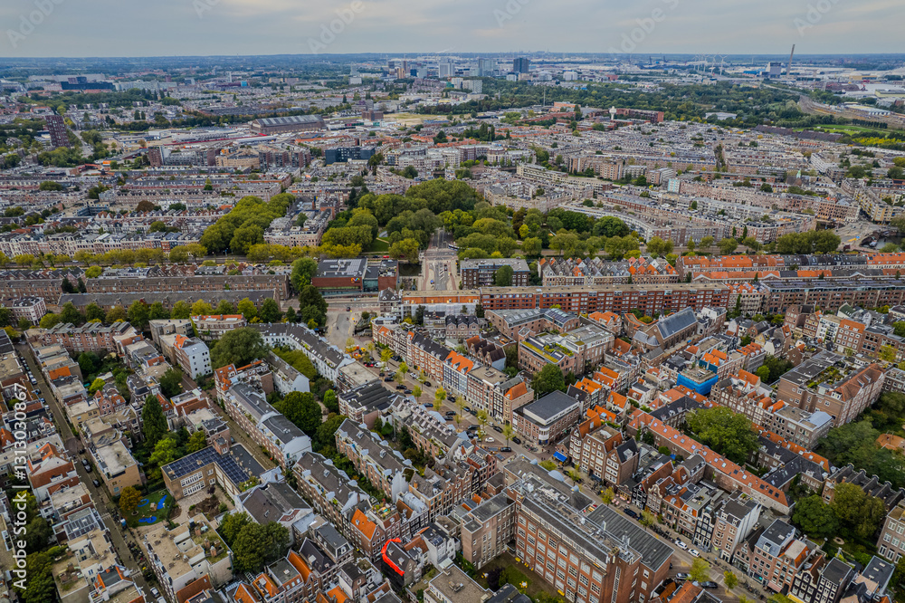 Obraz premium Aerial view of Amsterdam, Netherlands showcases its iconic canal houses, Dutch architecture, and boat tours along the waterfront, capturing the charm of this historic European cityscape