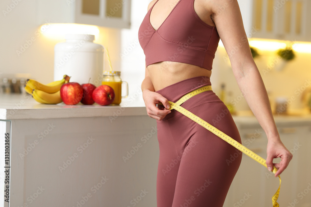 Φωτογραφία Weight loss. Woman measuring waist with tape in kitchen, closeup