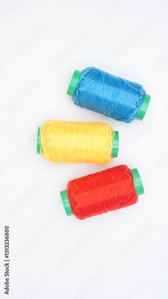 Blue, red, and yellow spool of sewing thread isolated on white background Blue, red, and yellow spool of sewing thread isolated on white background