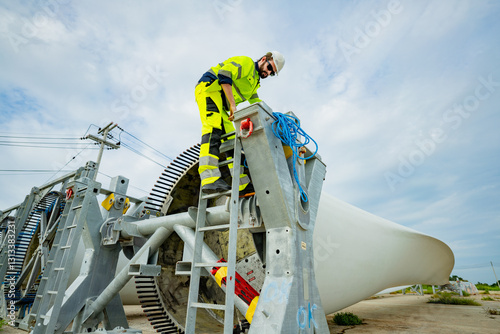 Worker climbs maintenance ladder to inspect large wind turbine generator in a renewable energy field