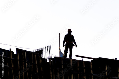 Construction site, silhouettes of construction industry workers on scaffolding against the sunset light. Constructing and building industry in Brazil