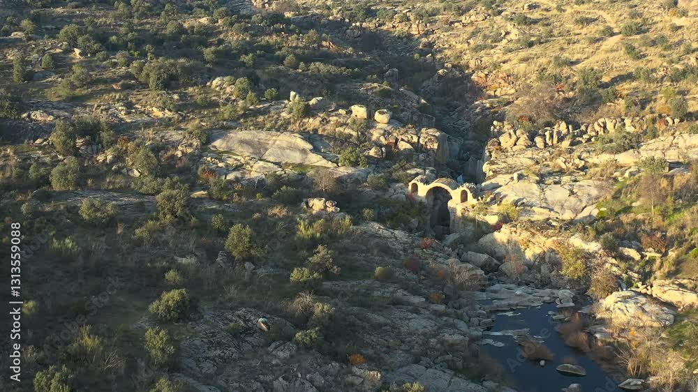 drone flight where we see a river and appreciate the remains of an old stone bridge from medieval times, with a large central arch over the course of the river, it is located in a rocky area drone flight where we see a river and appreciate the remains of an old stone bridge from medieval times, with a large central arch over the course of the river, it is located in a rocky area