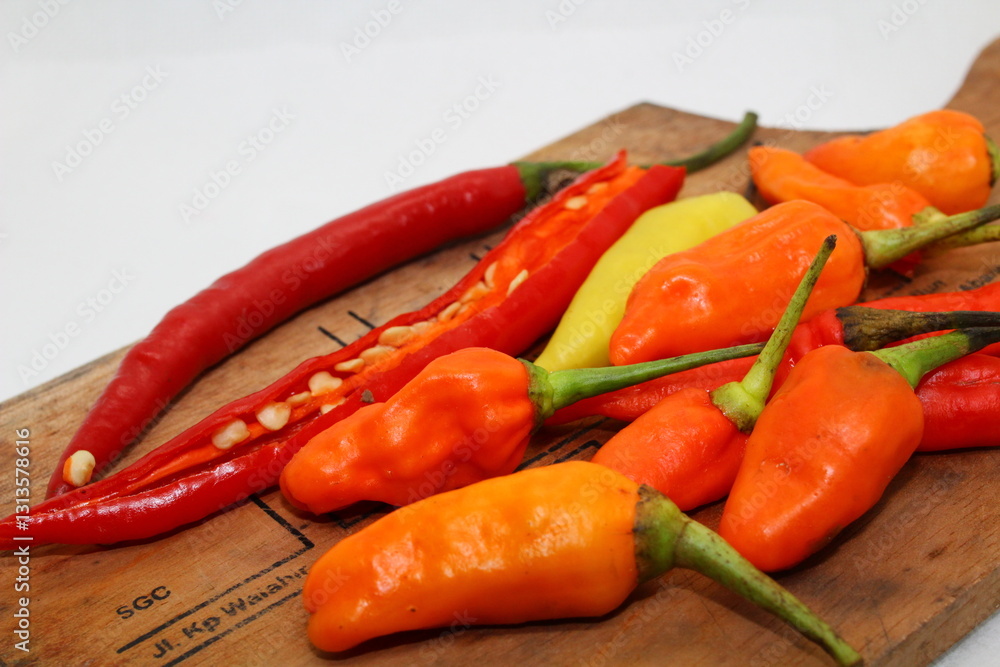 Fresh red and orange chili peppers on a rustic wooden