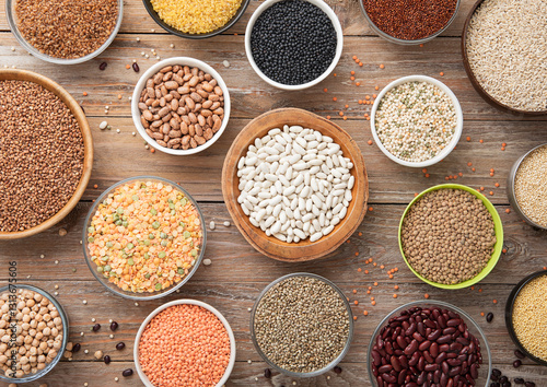 Bulgur,beans,quinoa,pea,couscous and hemp with chickpea and buckwheat seeds in various bowl plates on wooden kitchen background.Macro.