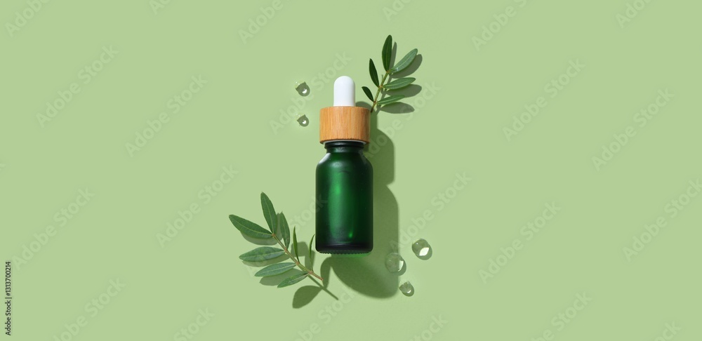 Fototapeta premium Bottle of essential oil, leaves and water drops on green background, top view