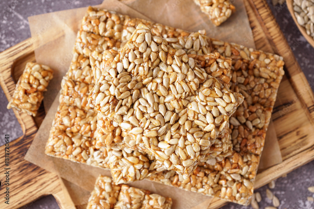 Board with tasty kozinaki and sunflower seeds on grunge grey background Board with tasty kozinaki and sunflower seeds on grunge grey background