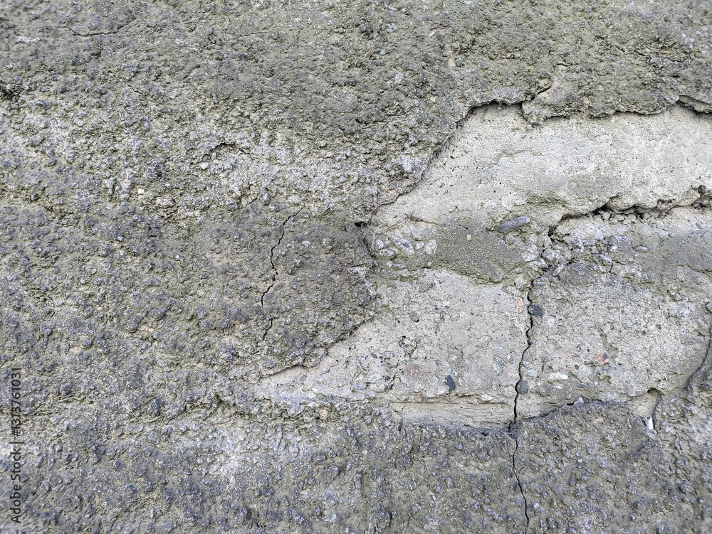 Fototapeta premium Gray uneven wall plastered with cement with a rough surface partially covered with light dirt. Blocks are visible on the right side