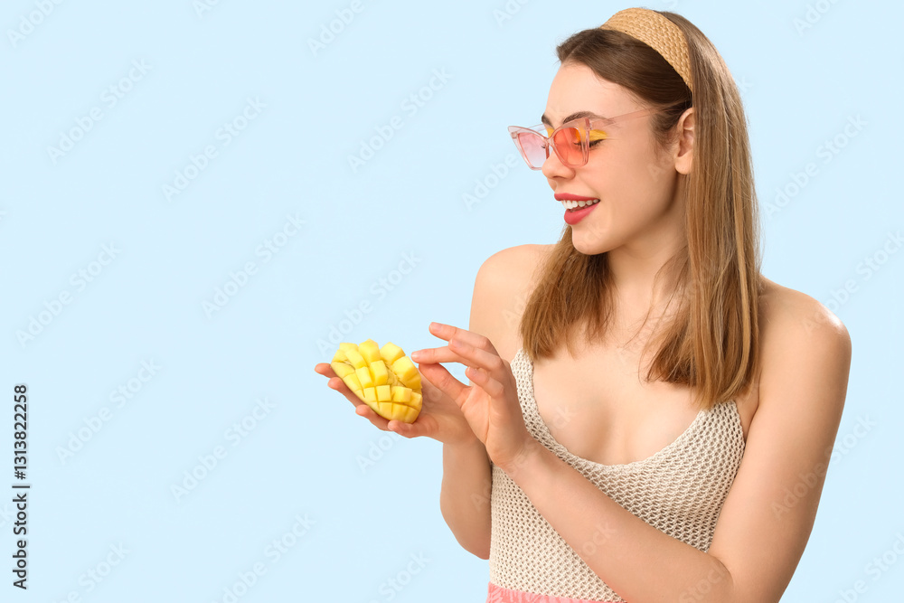 Beautiful young woman with cut sweet mango fruit on blue background Beautiful young woman with cut sweet mango fruit on blue background
