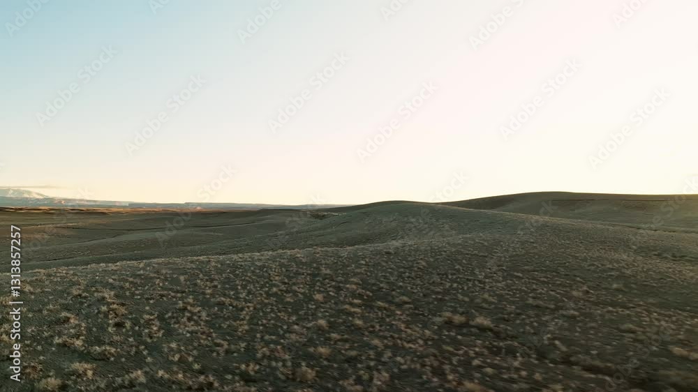 Aerial tracking of an SUV driving through an empty desert road at sunset, vast open landscape Aerial tracking of an SUV driving through an empty desert road at sunset, vast open landscape