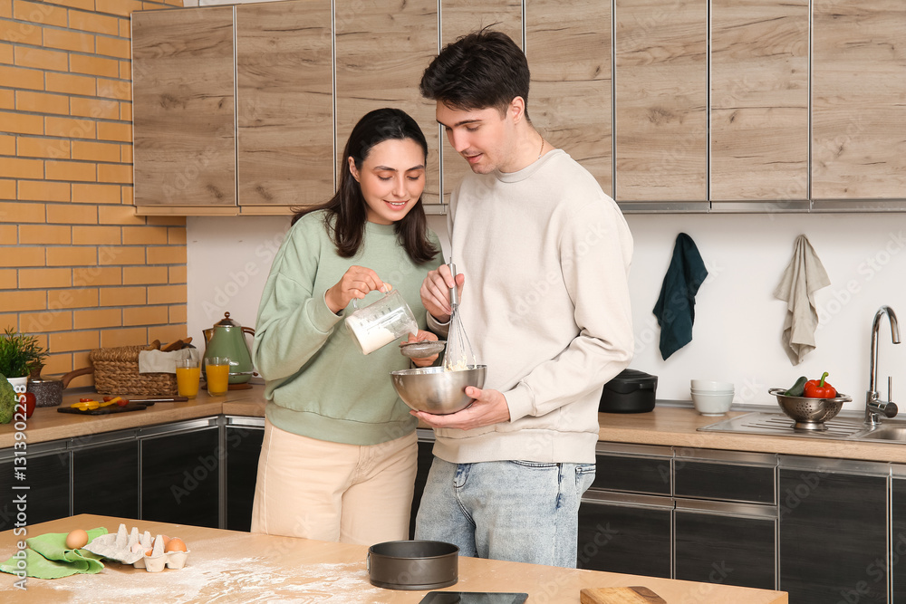 Fotografie Happy young couple sifting flour in kitchen