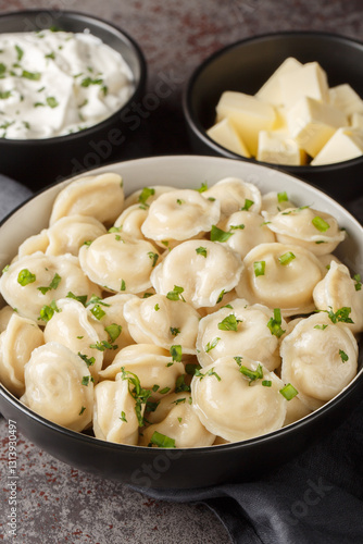 Obraz na płótnie Hot boiled Russian pelmeni served with sour cream, butter and herbs close-up on the table. Vertical w salonie