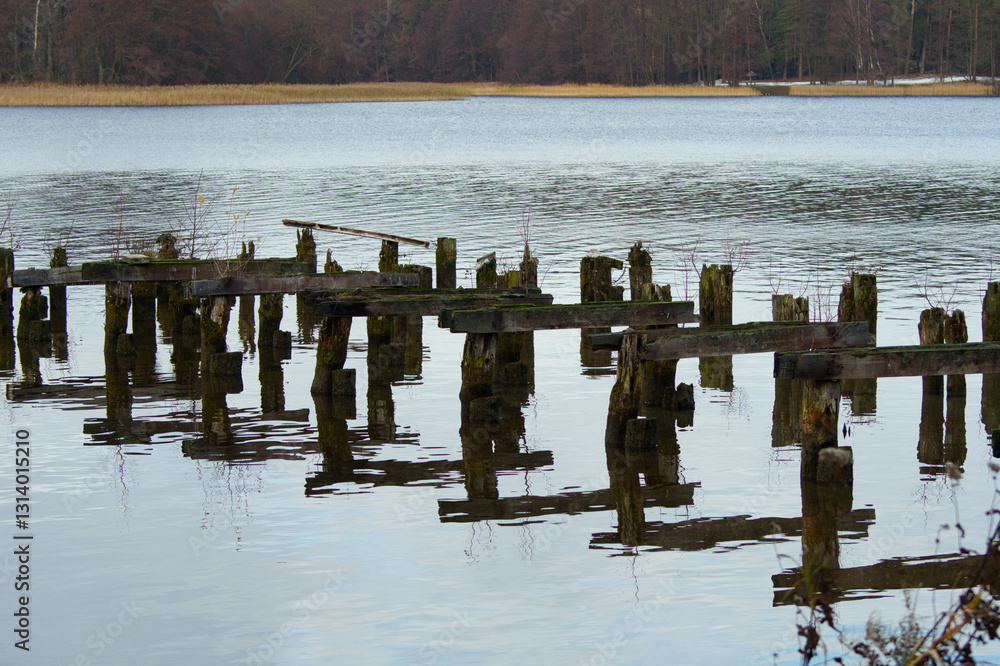 Rotten wooden pillars of a destroyed pier by Lake Białe, near Augustów, Poland. Rotten wooden pillars of a destroyed pier by Lake Białe, near Augustów, Poland.