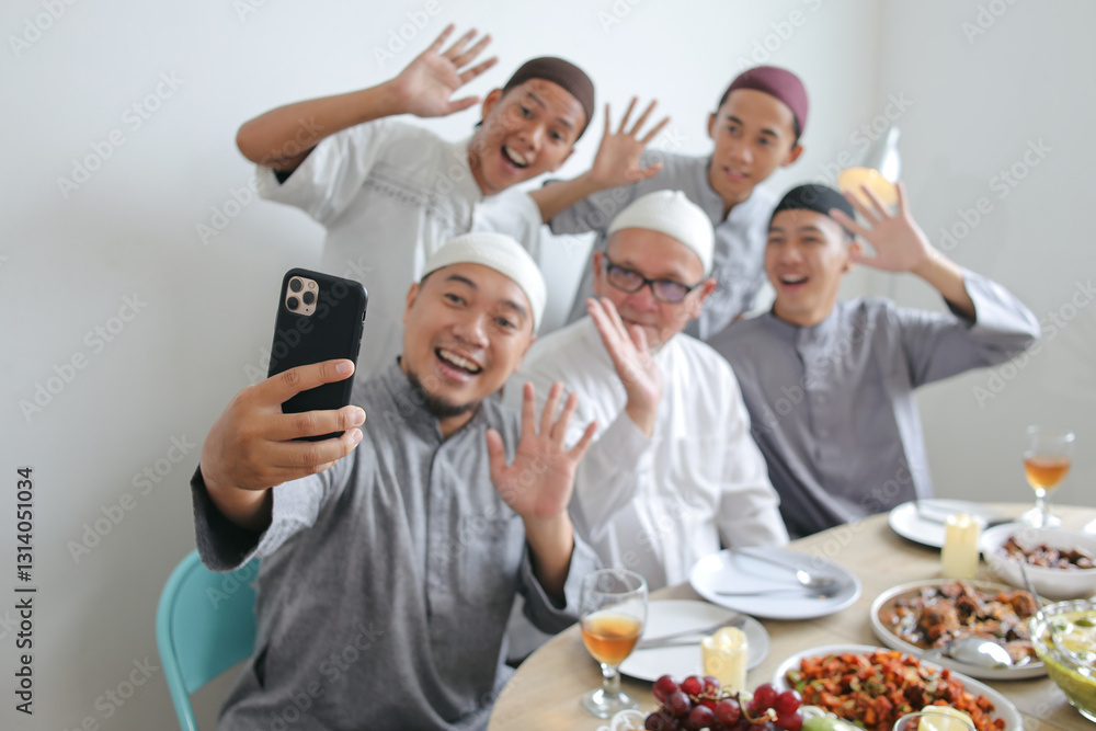 Obraz premium Multi Generation Muslim Family Selfie Using Smartphone At Dining Room Celebrating Eid Al Fitri