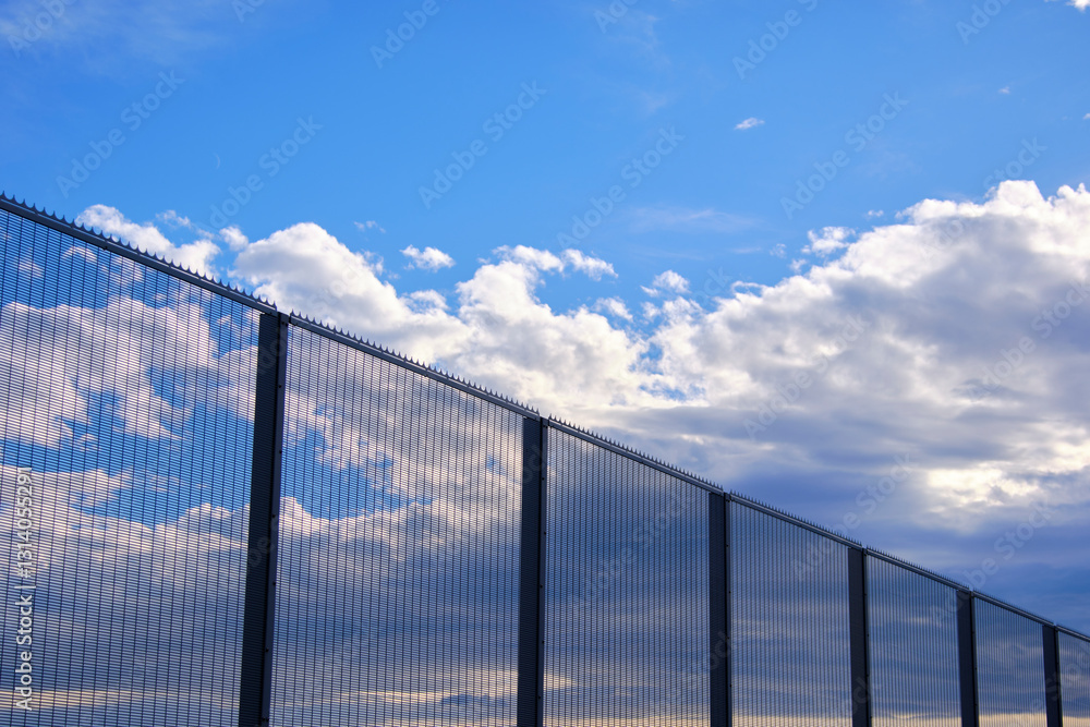 Security fence reflecting clouds and sky in airport perimeter Security fence reflecting clouds and sky in airport perimeter