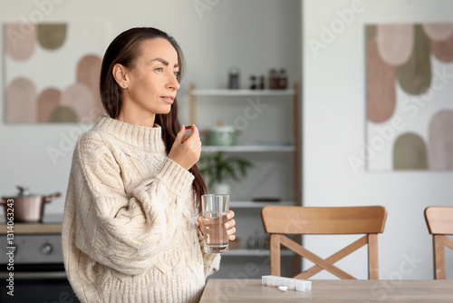 Woman taking medicine in ki...