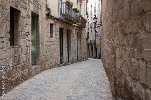 Cobblestone street winding between historic buildings. Aged stone walls, balconies, and perspective
