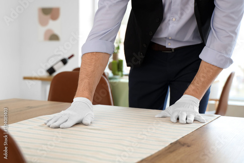 Male waiter putting cloth o...