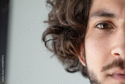 Obraz na plátně Close-up of young man showing half face with brown eyes and curly hair