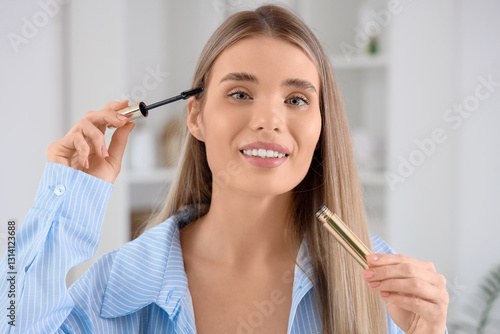 Young woman applying mascar...