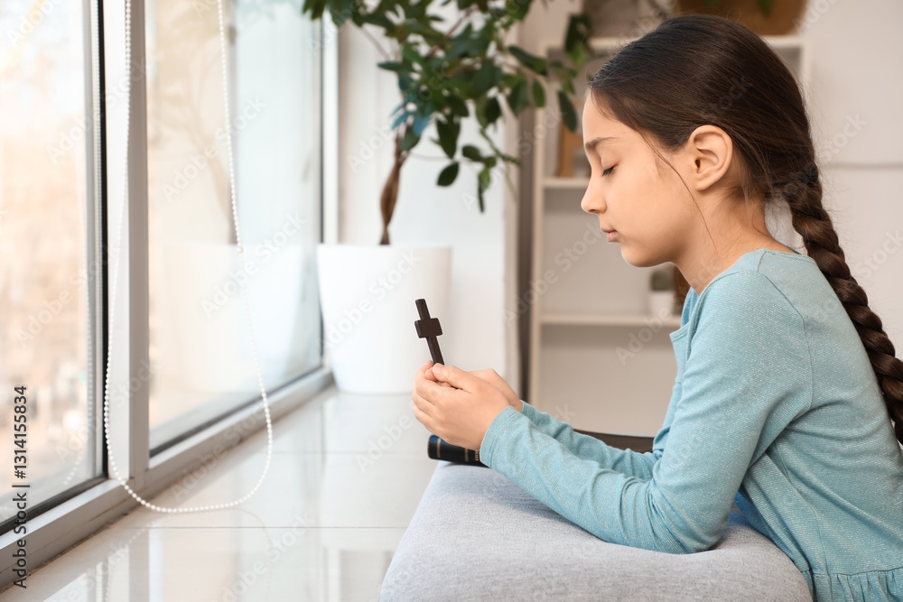 Little girl with cross praying at home Little girl with cross praying at home