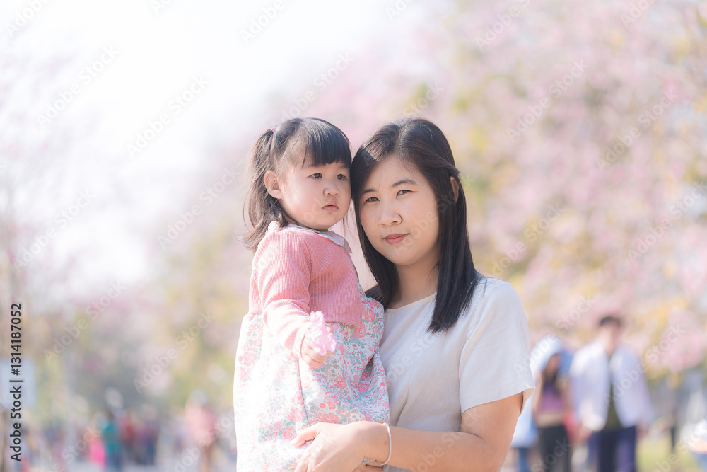 Smiley parent and child,Asian mother and daughter walking in a park with cherry trees. Smiley parent and child,Asian mother and daughter walking in a park with cherry trees.