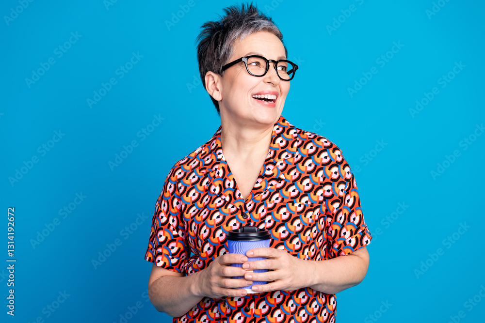 Mature Woman Smiling Cheerfully Holding a Coffee Cup Against a Vibrant Blue Background Highlighting Stylish Fashion and Relaxed Leisure Mature Woman Smiling Cheerfully Holding a Coffee Cup Against a Vibrant Blue Background Highlighting Stylish Fashion and Relaxed Leisure