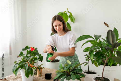 Joyful florist hydrating lush houseplants with a spray bottle.
