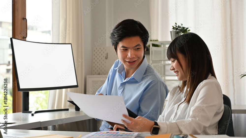 A young professional team shares a discussion, reviewing documents and color samples. Their smiles and engagement reflect teamwork, creativity, and a positive work