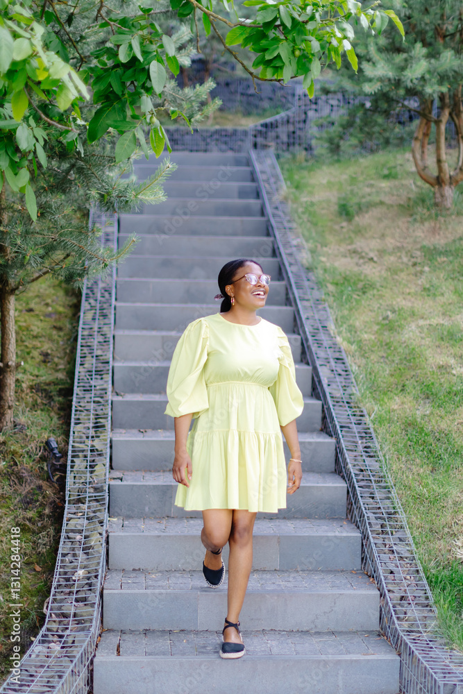 Dark-skinned lady laughs outside. Brunette woman in yellow dress smiles and walks outdoors Dark-skinned lady laughs outside. Brunette woman in yellow dress smiles and walks outdoors