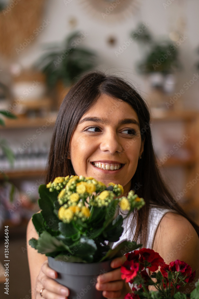 Portrait of a young happy dark-haired woman sitting in a studio with flowers and indoor plants.The spring concept,home gardening.