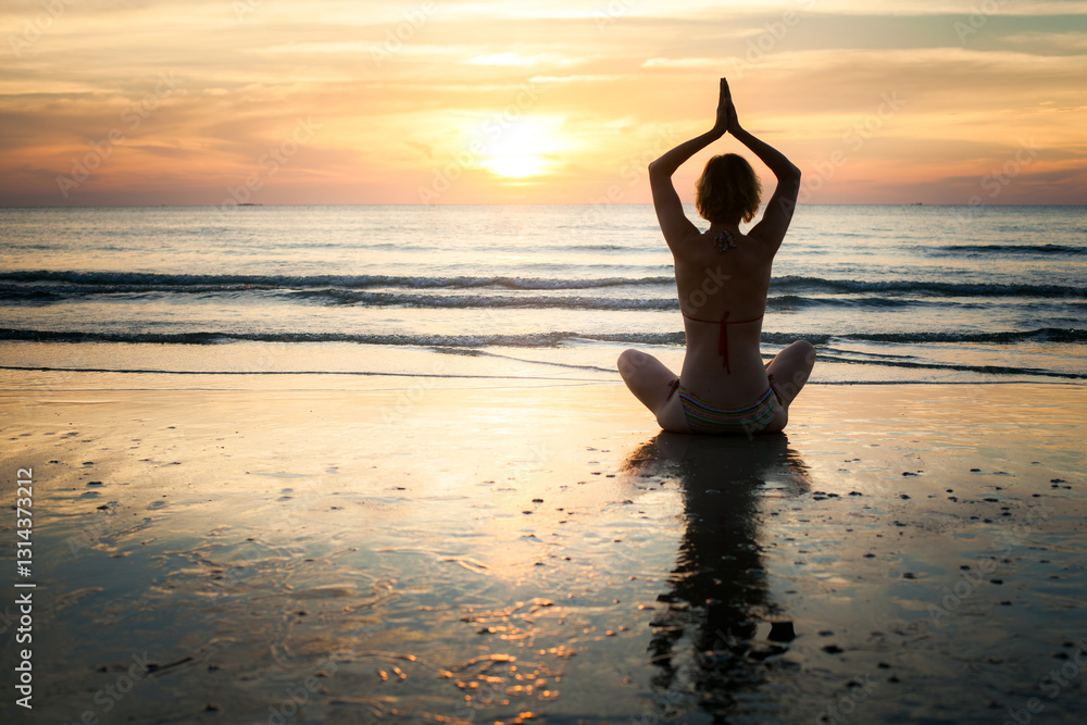 The silhouette of a woman meditating at the water's edge during a serene sea sunset, radiating peace and tranquility.