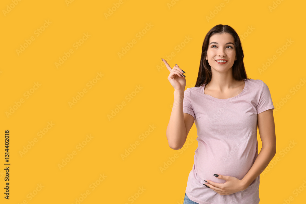 Happy pregnant woman pointing at something on yellow background Happy pregnant woman pointing at something on yellow background