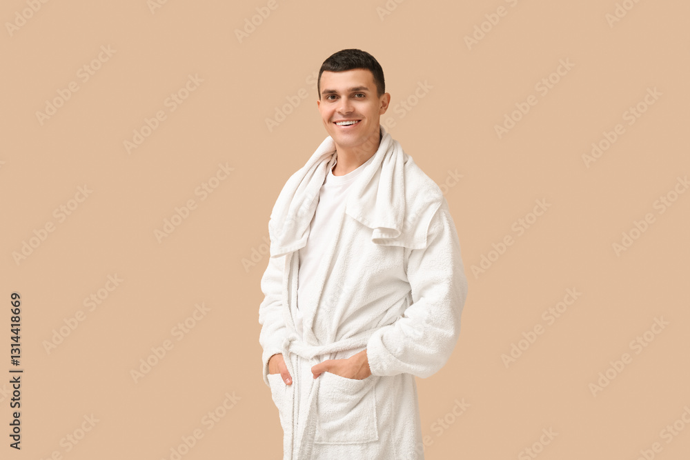 Portrait of handsome young man in bathrobe and towel on beige background Portrait of handsome young man in bathrobe and towel on beige background