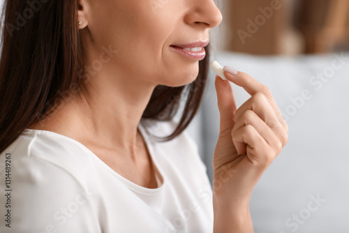 Woman taking pill in room. ...