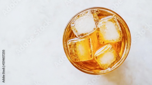 Overhead shot of a glass filled with golden lemon iced tea, ice cubes floating, crisp white background
