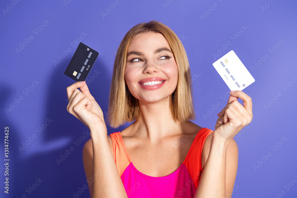 Smiling young woman holding credit cards displaying gestures against violet background for lifestyle and business concept Smiling young woman holding credit cards displaying gestures against violet background for lifestyle and business concept