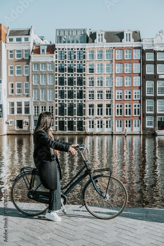 Φωτογραφία Une femme sur un vélo en face des maisons dansantes dans la ville de Amsterdam a