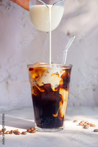 pouring milk into a glass of homemade iced cold brew coffee, white cold brew. .