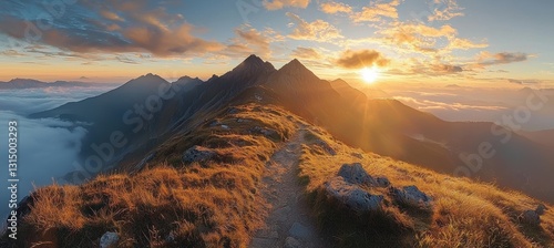 Golden hour sunlight bathes a winding hiking path along a mountain ridge in the tatra mountains, poland, with panoramic views of peaks and clouds