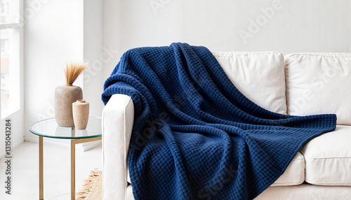 Luxurious navy blue blanket draped on modern white sofa, cozy elegance