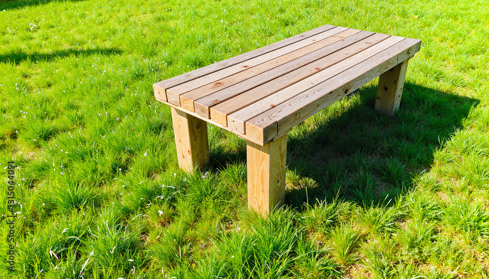 Fototapeta premium Wooden table on green grass under natural sunlight, outdoor relaxation