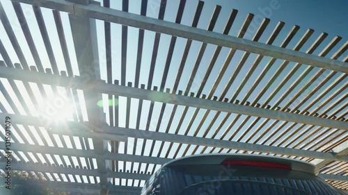 Vehicles on covered parking lot, striped metal construction frame protecting cars, trucks and motorcycles from scorching sun and heavy thunderstorm