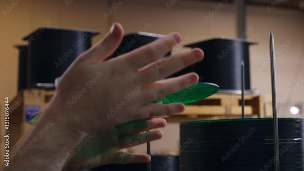 Hands in motion as a green vinyl record is being checked at a record pressing factory. Hands in motion as a green vinyl record is being checked at a record pressing factory.