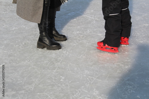 legs of a woman and child skating in winter