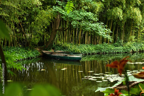 Bamboo trees by pond with canoe in Monet's Garden on a summer day in Giverny, France.