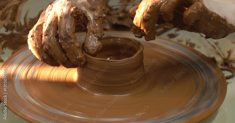 The potter's wheel. A close-up of the hands of a craftsman skillfully working with clay on a potter's wheel, giving it the shape of a clay product